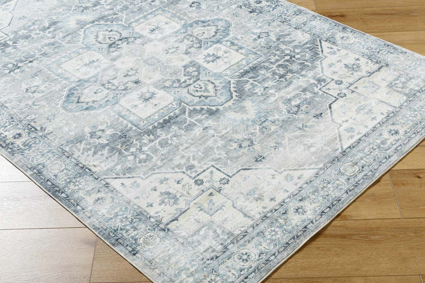 Close-up of the Mauro Blue Medallion Washable Area Rug showing its light gray, silver, and blue traditional design. Corner