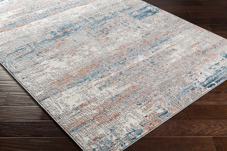 Close-up of McCracken Area Rug: contemporary design in white, blue, and coral on dark wood floors. Abstract pattern, machine woven. Corner
