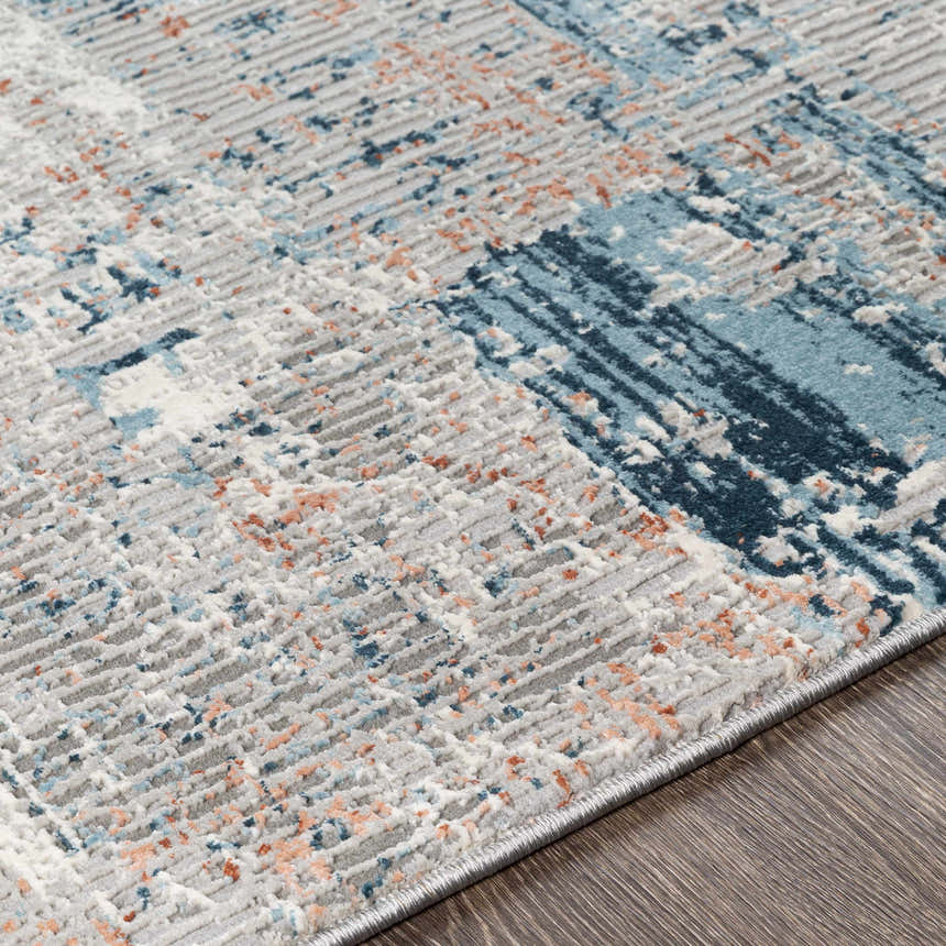 Close-up of the McCracken Area Rug showing its textured weave and abstract pattern in gray, blue, and coral. Texture