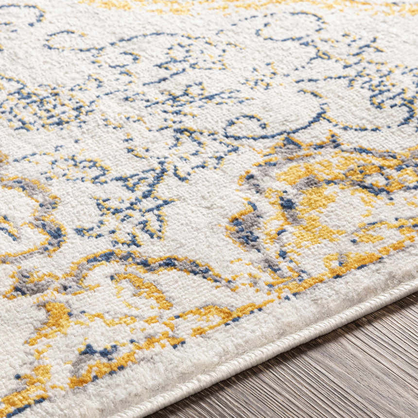 Close-up of the Mehoopany Area Rug. Features a light beige base with navy, gray, and mustard bohemian-inspired patterns. Texture