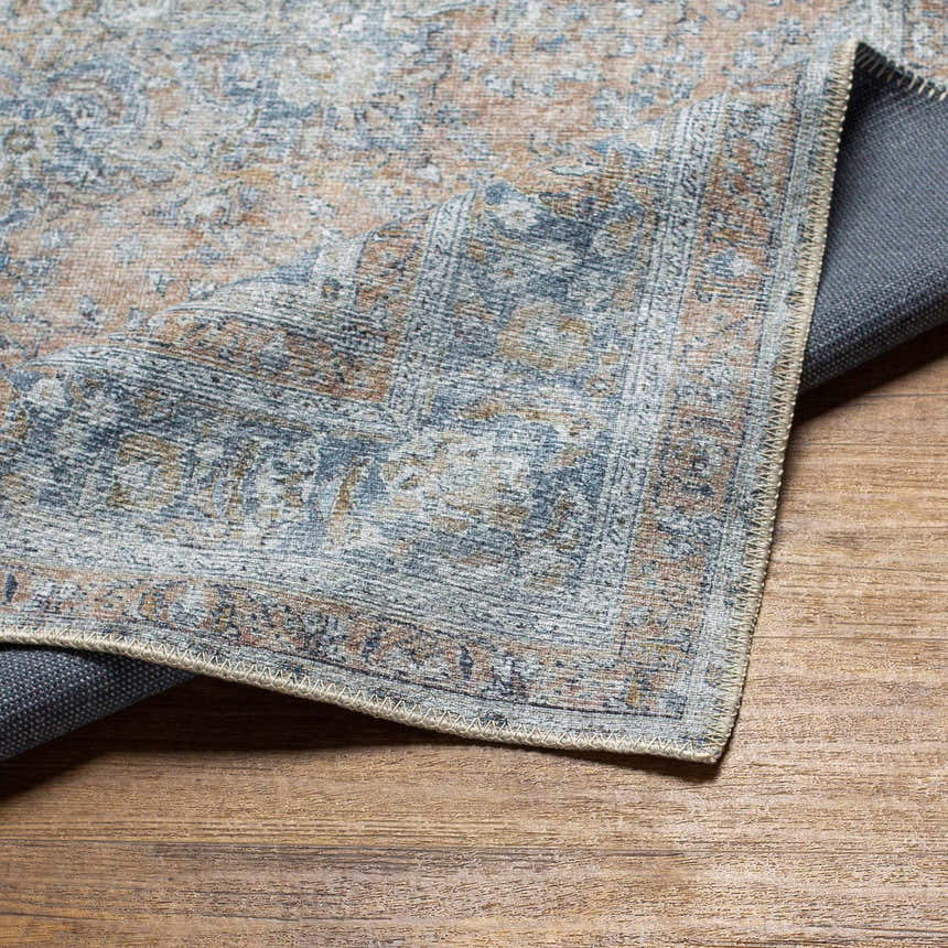 Close-up of the Mianay Washable Area Rug, showcasing its vintage-style pattern in beige, blue, and light gray hues. Fold