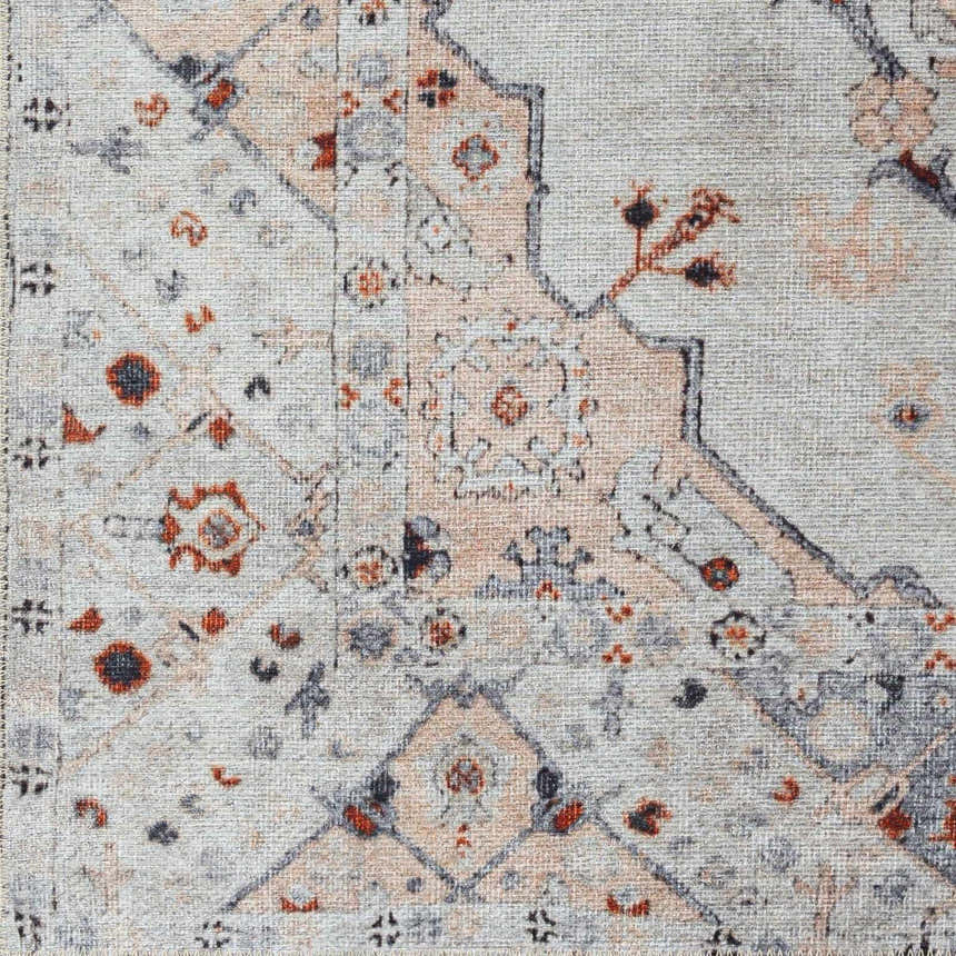 Close-up of the Midtown Washable Area Rug. Features a traditional pattern in brick red, charcoal, gray, and peach tones. Texture