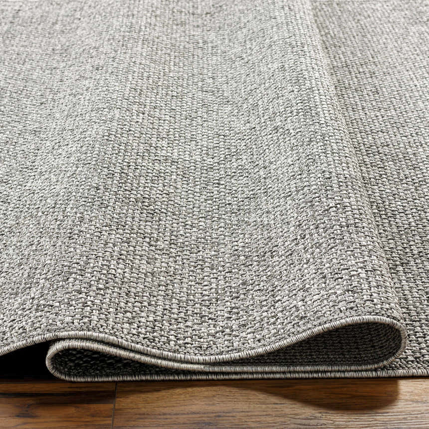 Close-up of the gray Medih Area Rug showing its woven texture and construction on a wood floor. Texture