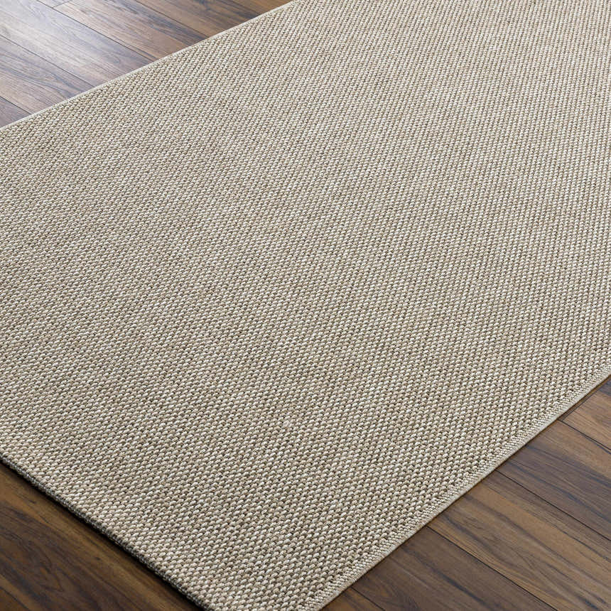Close-up of the woven texture and neutral beige color of the Matah Beige Outdoor Area Rug on a dark wood floor. Corner
