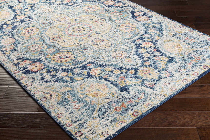 Close-up of the Mallacoota Area Rug. Traditional design with cream, navy, yellow, rose, and sky blue colors. Corner