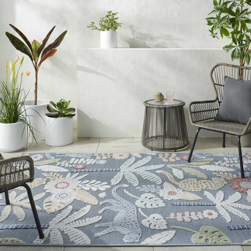 Indoor patio with blue Micha Area Rug, wicker chairs, side table, and potted plants. Floral and animal pattern. Roomscene-Rectangle