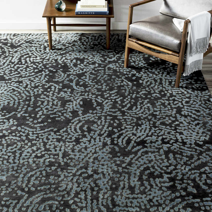 Contemporary room scene with a Pensacola Denim/Black rug, wood chair, and side table. Styleshot