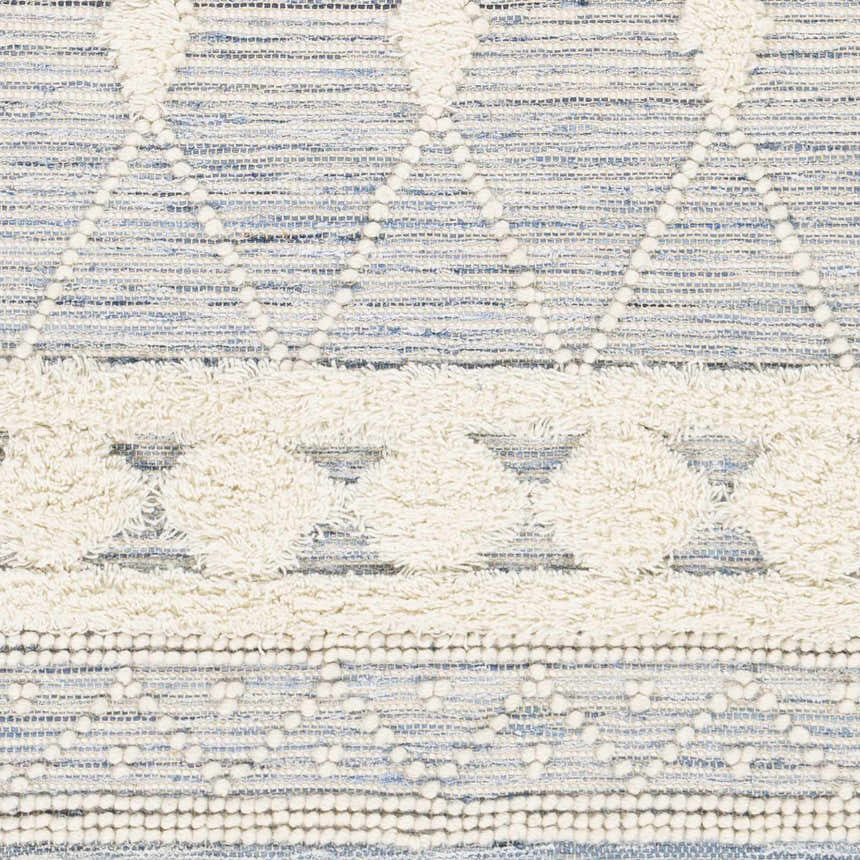 Close-up of the Moe Area Rug showing its hand woven texture and bohemian blue, cream, and white pattern. Swatch