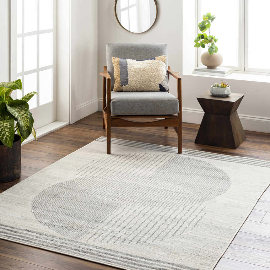 Living room scene with gray chair and the Amar Area Rug in dark gray and natural gray. Roomscene-Rectangle