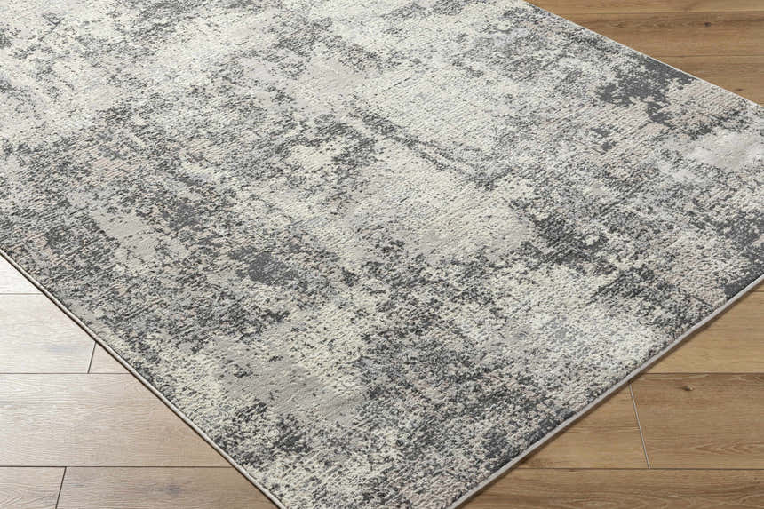 Close up of Marci Area Rug. Southwestern style rug in charcoal, cream, gray, and peach on hardwood floor. Corner