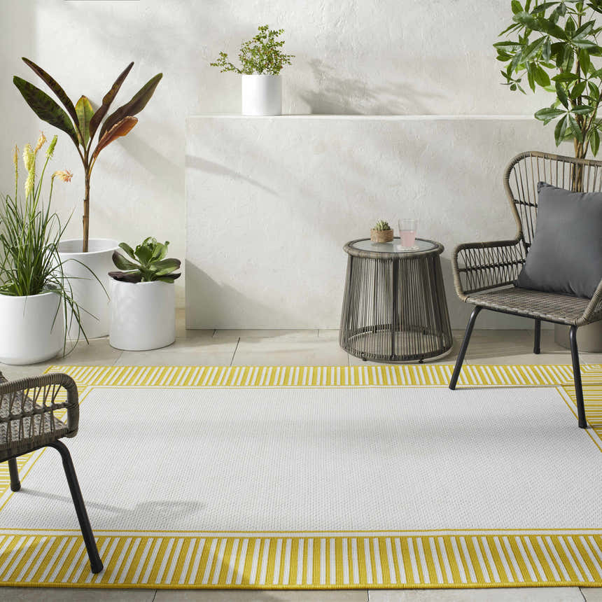 Outdoor patio scene with a cream Nadir Area Rug featuring a yellow striped border. Roomscene-Rectangle