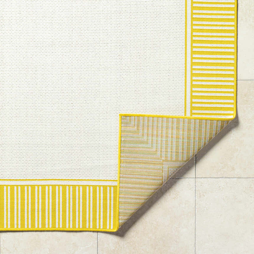 Close-up of Nadir Area Rug. Cream rug with yellow and white striped border. Machine woven olefin rug. Fold