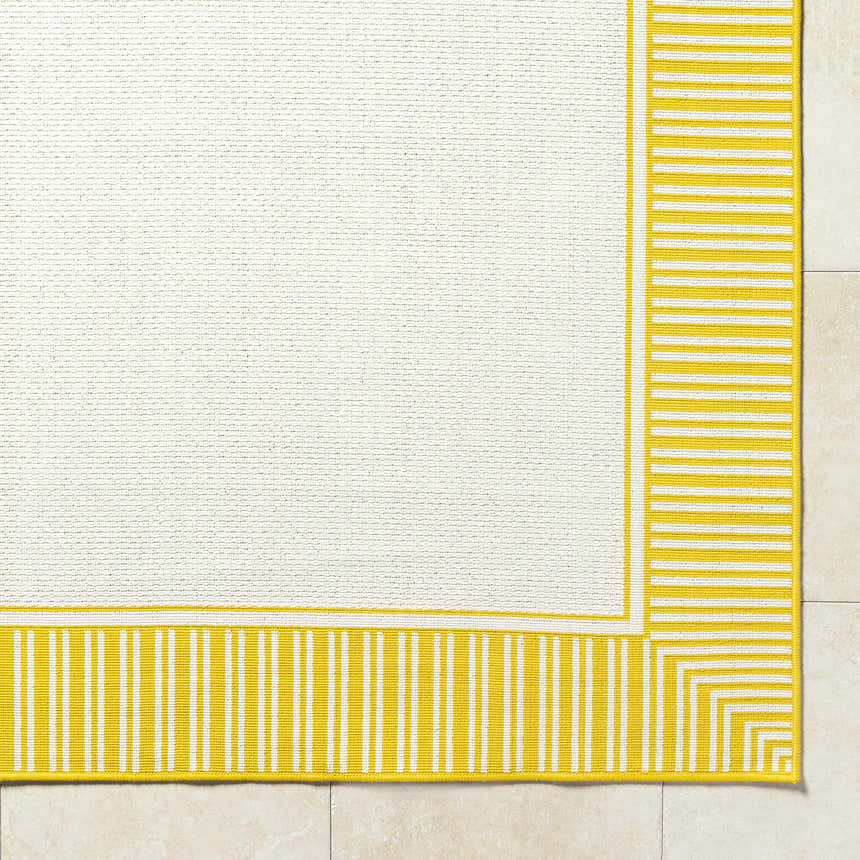 Close-up of the Nadir Area Rug. Cream rug with a yellow striped border on a tile floor. Corner