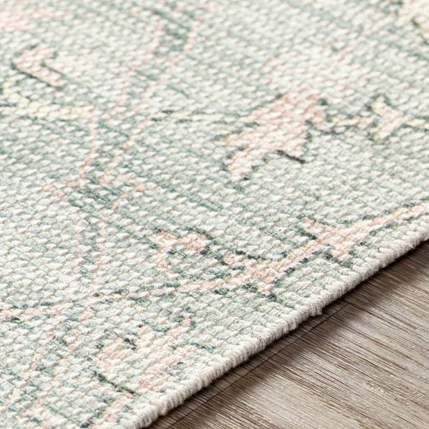Close-up of Enderby rug showing hand-woven texture and bohemian pattern in dark green, sage, olive, light pink, and white. Texture