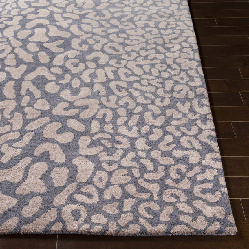 Close-up of the Neoma Animal Print Wool Rug. Gray background with a light tan animal print pattern. Hand-tufted texture. Front