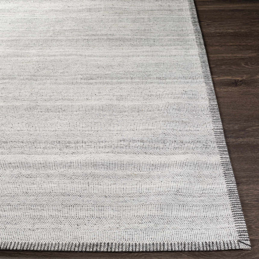 Close-up of Nettleham Silver Viscose Rug showing charcoal, medium gray, and silver gray horizontal stripes on dark wood floor. Front