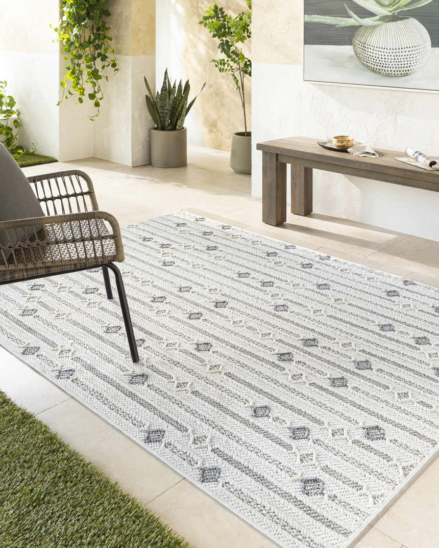 Serene patio scene with ivory and gray Niara Area Rug, wicker chair, and potted plants. Roomscene-Rectangle
