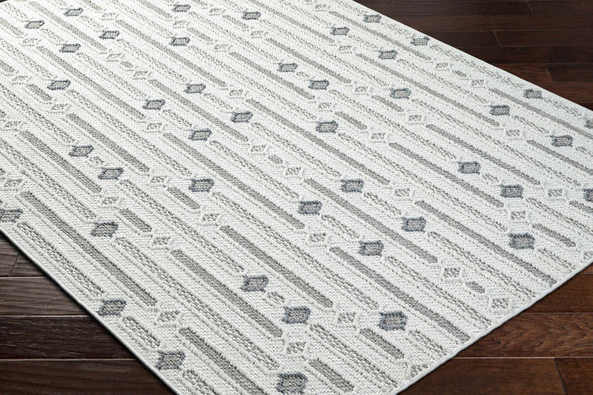 Close-up of Niara Area Rug. Contemporary style with ivory, light and medium gray stripes and geometric shapes. Corner