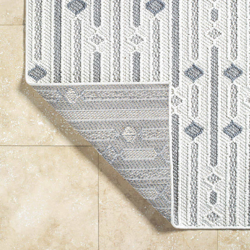 Close-up of the Niara Area Rug showing its ivory and gray geometric pattern and textured, machine-woven construction. Fold