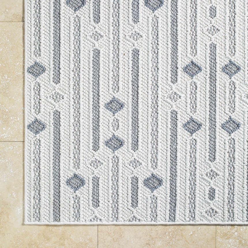 Close-up of the Niara Area Rug. Ivory, light gray, and medium gray geometric pattern. Machine woven polyester rug. Corner