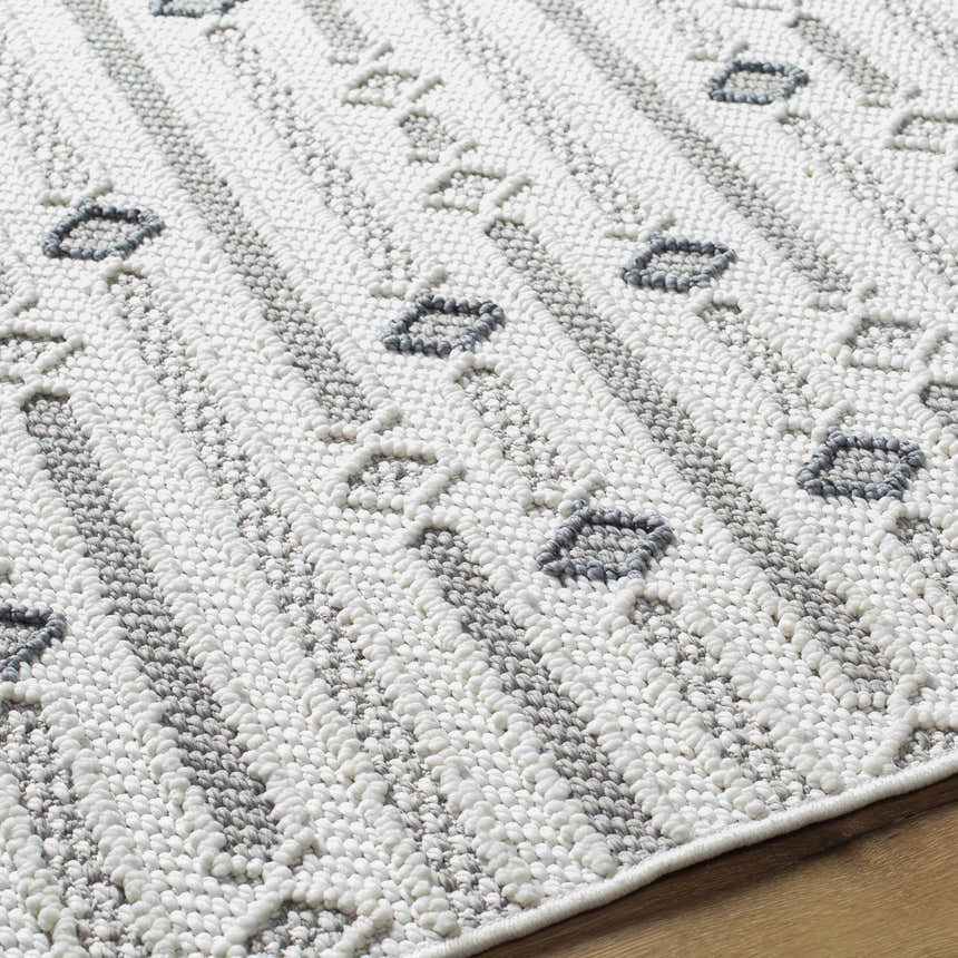 Close-up of the Niara Area Rug. Ivory rug with light and medium gray stripes and geometric diamond pattern. Contemporary style. Texture