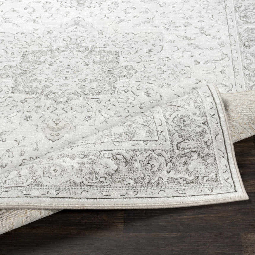 Close-up of the Okehampton Area Rug, a farmhouse-style runner in charcoal, light gray, and white, on dark wood flooring. Fold