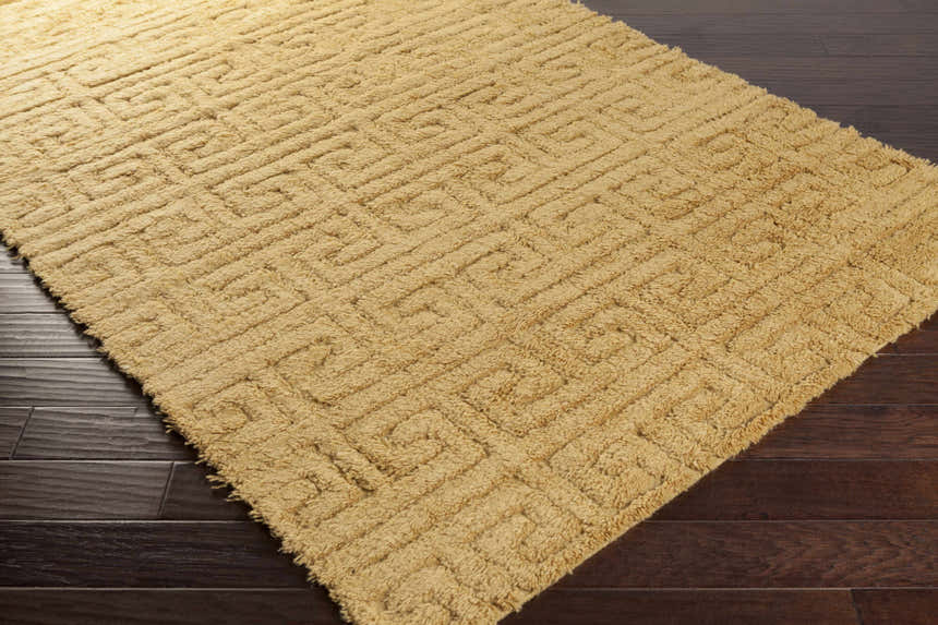 Close-up of the Omagh Area Rug in mustard. Hand-woven wool shag rug with a geometric Greek key pattern. Corner