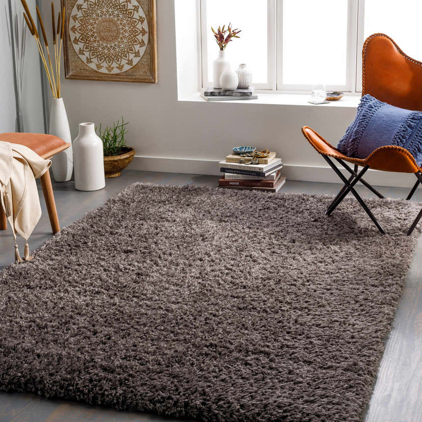 Living room scene with a charcoal Siari Solid Shag Rug, leather chair, and neutral decor. Roomscene-Rectangle