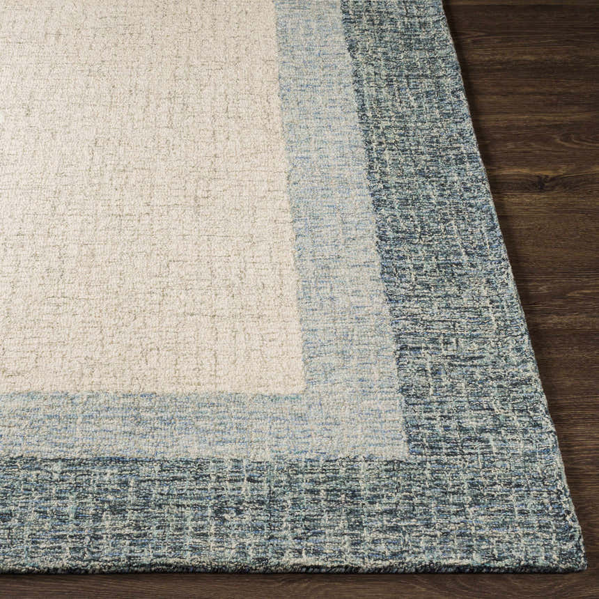 Close-up of the hand-tufted Padada Green Bordered Cream Wool Rug showing the cream center and blue border detail. Front