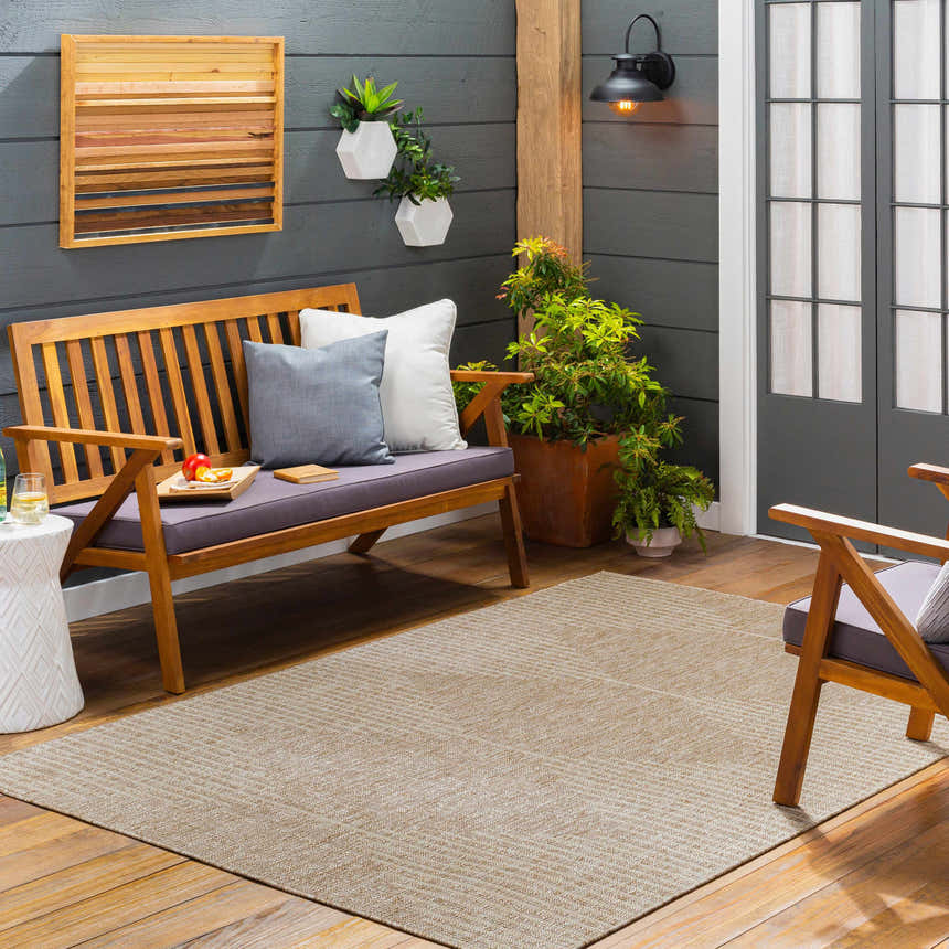 Outdoor patio scene with a Stephan Dark Beige Outdoor Rug, wood bench, and gray accent pillows. Roomscene-Rectangle