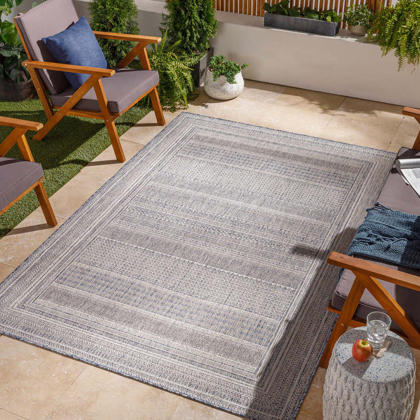 Outdoor patio scene with a charcoal and cream Panaytayon area rug, wood chairs, and potted plants. Roomscene-Rectangle