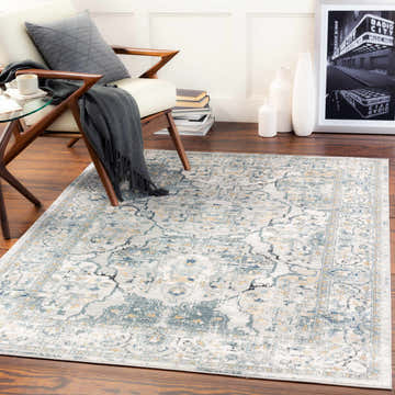 Living room scene with a Parcoal Area Rug in beige, blue, and gray, styled with a modern chair and dark wood floors. Roomscene-Rectangle