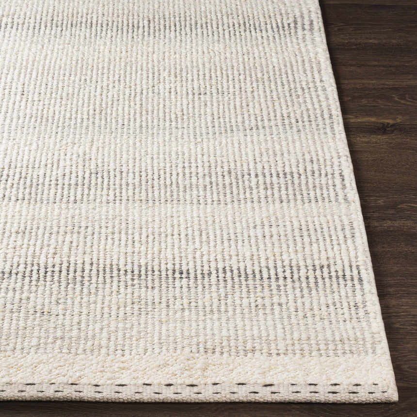 Close-up of the textured Penticton Cream Flat Woven Wool Rug showing its cream, beige, and gray tones on a dark wood floor. Front