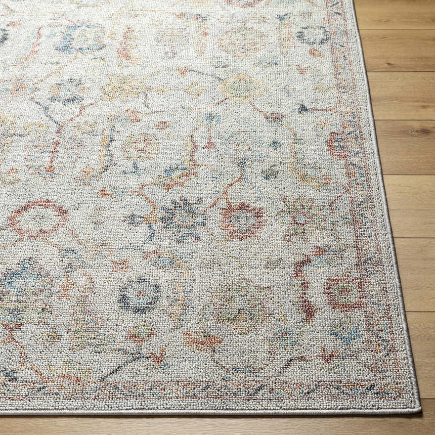 Close-up of Piera Washable Area Rug in ash, light gray, and silver. Traditional floral pattern on a textured polyester rug. Front
