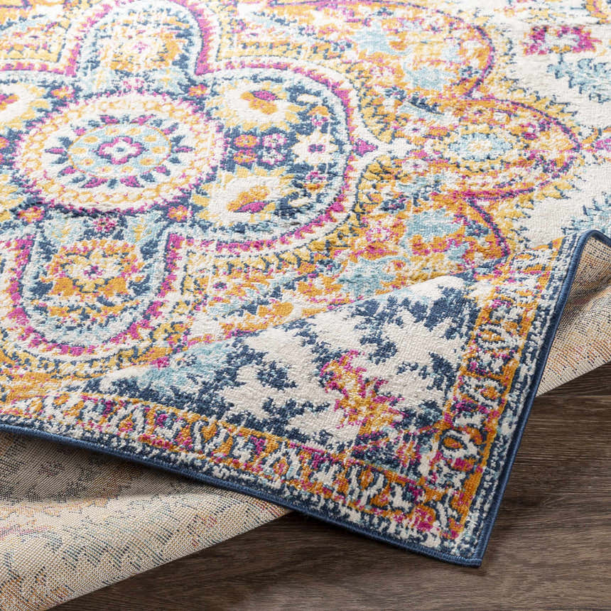 Close-up of the Pimperne Traditional Medallion Area Rug showing burnt orange, fuchsia, and navy floral pattern. Fold