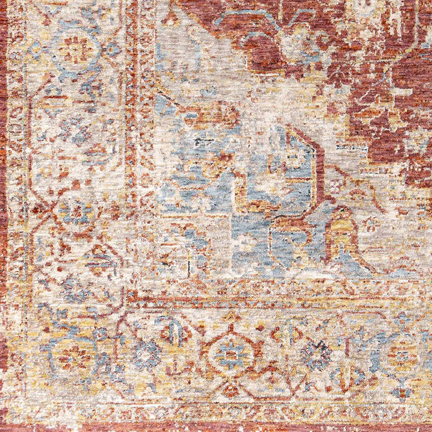 Close-up of the Powassan Area Rug showcasing its brick red, teal, and beige traditional pattern and soft texture. Swatch