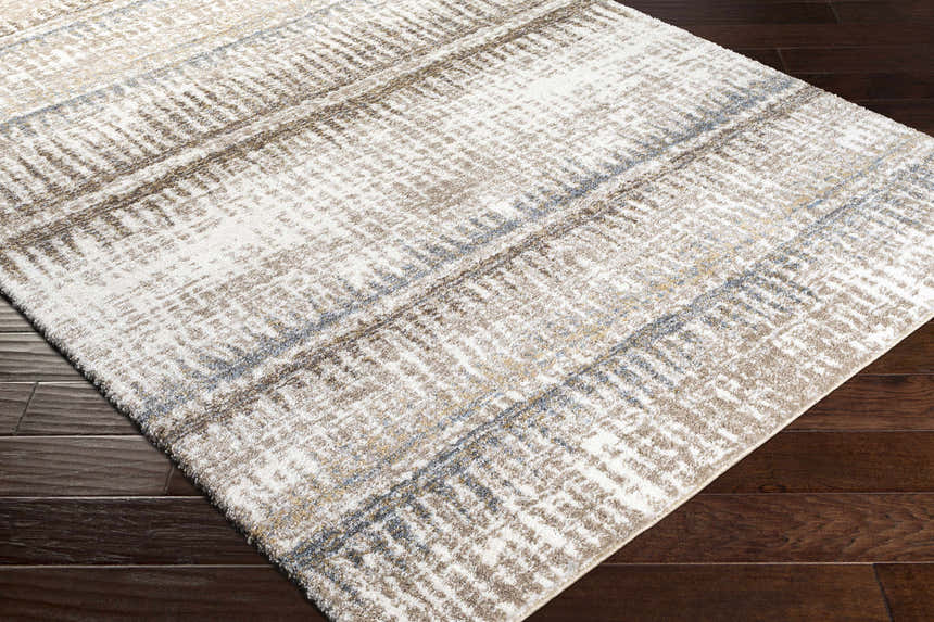 Close-up of the Prees Area Rug, showcasing its contemporary cloud gray, cream, and brown geometric pattern and soft texture. Corner