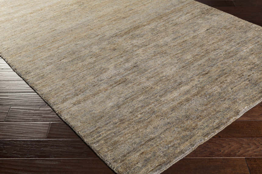 Close-up of gray Provencal Jute Rug showing texture and hand-knotted construction on dark wood floor. Contemporary style. Corner
