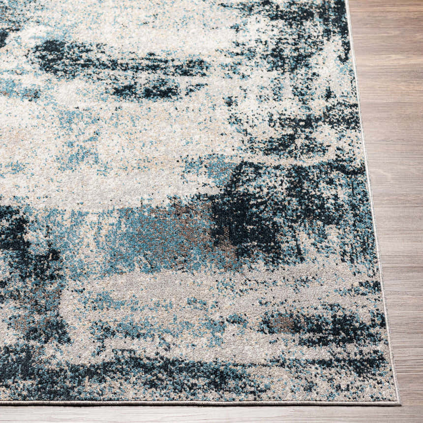 Close-up of the Pugo Washable Area Rug showing its blue, cream, and ink blue contemporary pattern and soft texture. Front