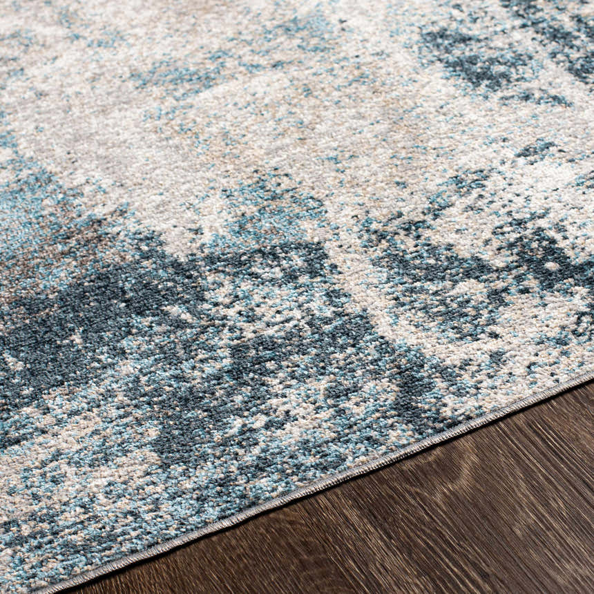 Close-up of the Pugo Washable Area Rug showing its blue, cream, and gray contemporary pattern and soft texture. Texture