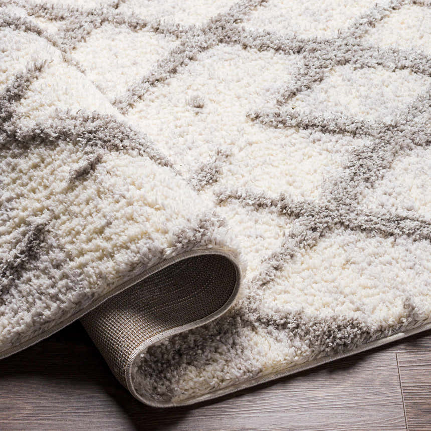 Close-up of the plush Putat Area Rug. Gray and white geometric pattern with a soft, textured pile. Fold