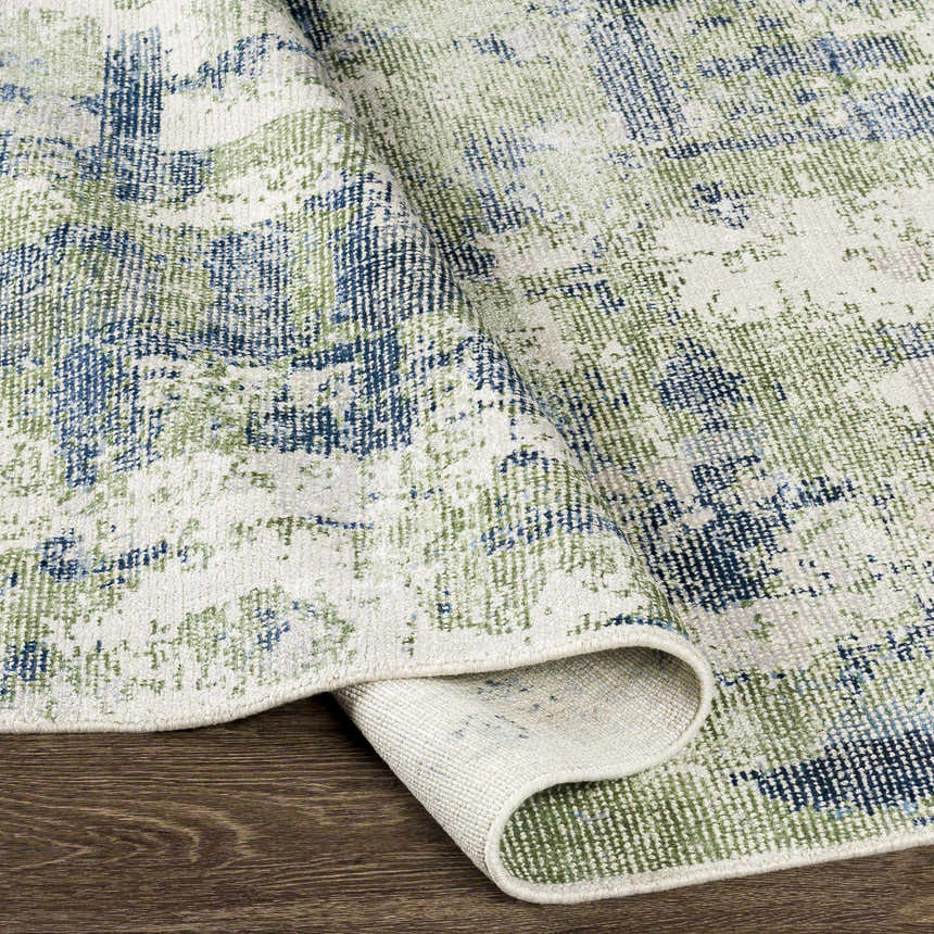 Close-up of the hand-knotted Pyle Area Rug. Features a contemporary design in beige, blue, sage, and teal. Wool and viscose blend. Fold