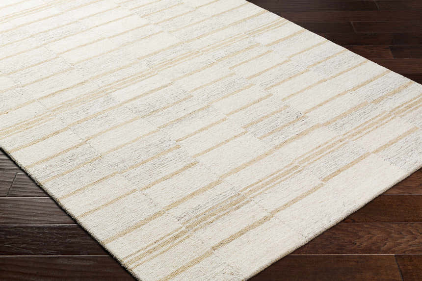 Close-up of the Paiva Modern Wool Rug. Cream rug with tan stripes on dark wood flooring. Corner