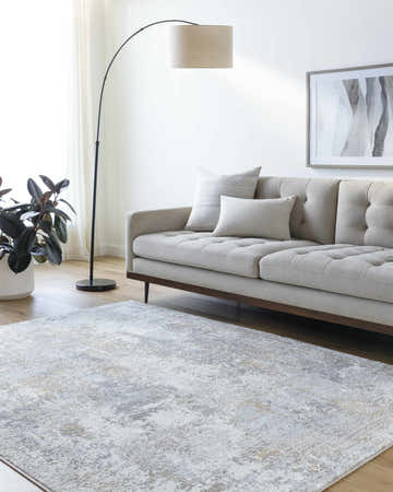 Living room scene with a light gray sofa and the charcoal, gray and taupe Ulani Area Rug. Roomscene-Rectangle