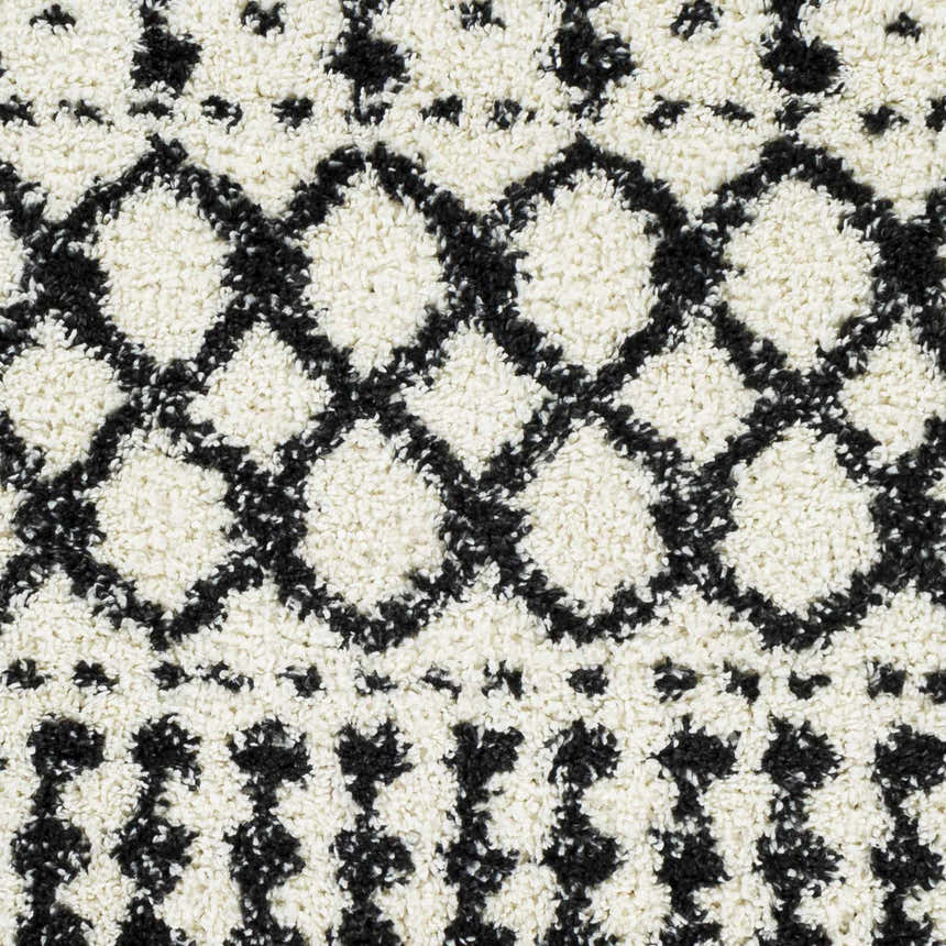 Close-up of the plush Walkern White/Black rug. Features a cream base with a black diamond and star-like geometric pattern. Swatch