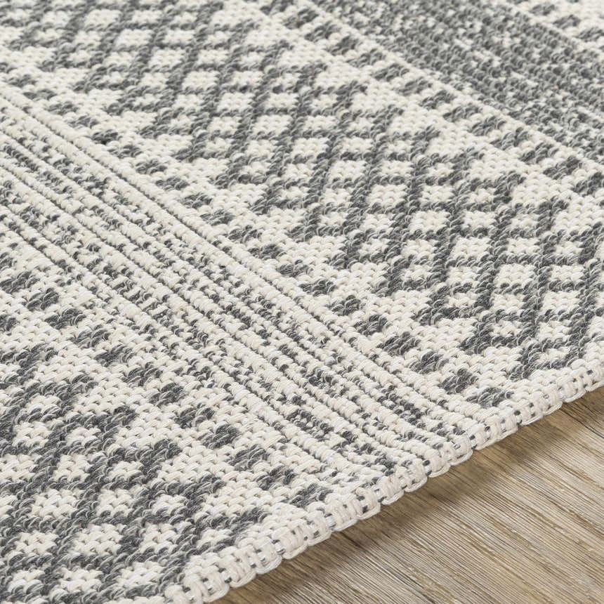 Close-up of the Ringtown Washable Area Rug. Charcoal and ivory cotton rug with a woven geometric pattern. Bohemian style. Texture