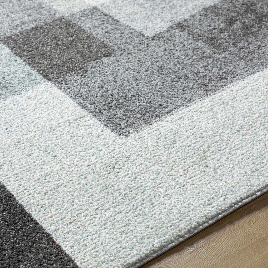 Close-up of the Raisa Area Rug showing its geometric pattern in aqua, black, cream, light gray, and light brown. Texture