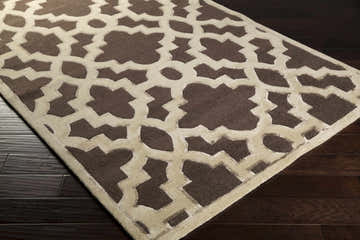 Close-up of the Rushford Area Rug featuring a brown and beige geometric pattern on dark wood flooring. Corner