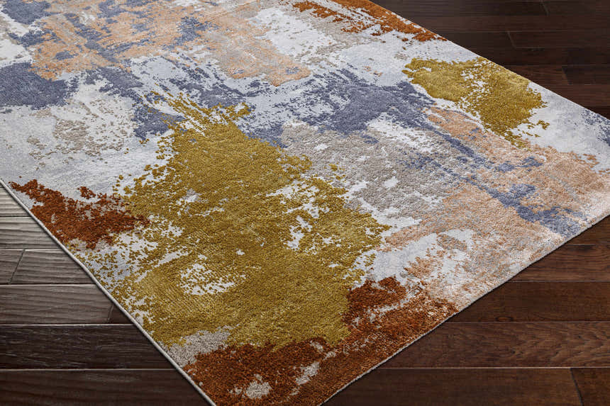 Close-up of Rivers Area Rug with abstract brick red, dark blue, mustard, and gray pattern on dark wood floor. Corner