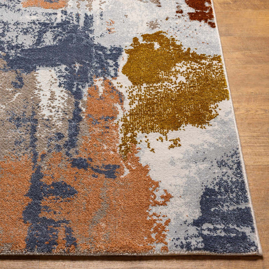 Close-up of the Rivers Area Rug showing brick red, dark blue, mustard, and gray abstract pattern and soft texture. Front